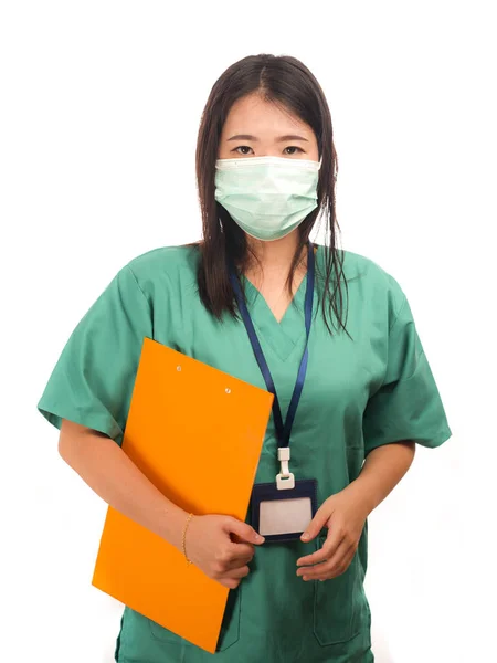 Young beautiful Asian Korean medicine doctor woman or hospital nurse holding clipboard  in scrubs using protective medical face mask in prevention against virus infection isolated — 스톡 사진