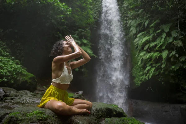 Junges attraktives und glückliches Hipstermädchen beim Yoga im Freien am wunderschönen tropischen Wasserfall meditiert und genießt Freiheit und Natur in einem gesunden und Zen-Lebensstil — Stockfoto