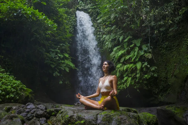 Junges attraktives und glückliches Hipstermädchen beim Yoga im Freien am wunderschönen tropischen Wasserfall meditiert und genießt Freiheit und Natur in einem gesunden und Zen-Lebensstil — Stockfoto