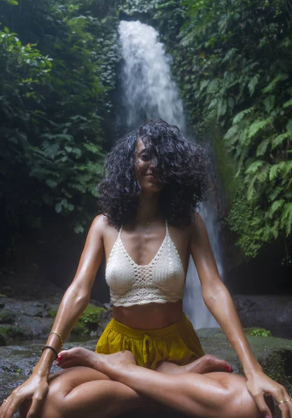 Giovane ragazza attraente e felice hipster facendo yoga all'aperto a bella cascata tropicale meditando godendo la libertà e la natura in stile di vita sano e zen — Foto Stock