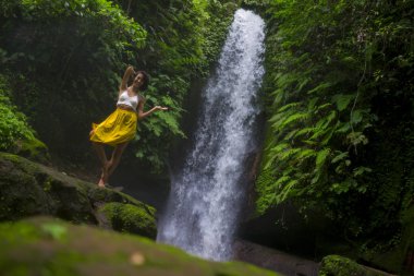 Genç, çekici ve mutlu hippi kadın doğanın tadını çıkarıyor. Egzotik tatil beldelerinde harika bir şelalede özgür hissediyor.