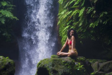 Genç, çekici ve mutlu hippi kadın doğanın tadını çıkarıyor. Egzotik tatil beldelerinde harika bir şelalede özgür hissediyor.