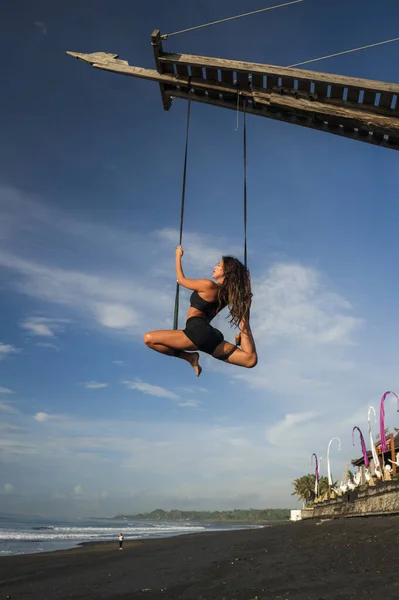 Aero Yoga Beach Workout - junge attraktive und athletische Frau übt Aerial Yoga Übungstraining akrobatische Körperhaltungen am blauen Himmel über dem Meer auf der Insel Bali — Stockfoto