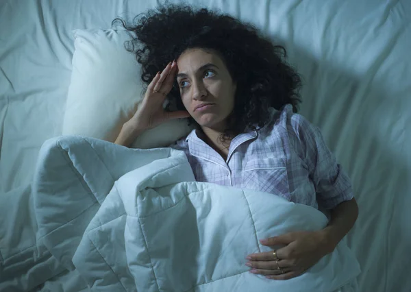 Muda sedih dan depresi wanita hispanik dengan rambut keriting tidur di tempat tidur terjaga dan perasaan bijaksana khawatir menderita masalah depresi dan gangguan insomnia — Stok Foto