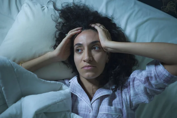 Jovem triste e deprimida mulher hispânica com cabelo encaracolado sem dormir na cama acordado e sentimento pensativo preocupado sofrendo problema de depressão e transtorno de insônia — Fotografia de Stock