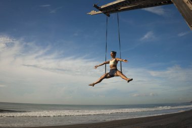Hava yogası plaj egzersizi. Genç, çekici ve sağlıklı bir kadın. Aero-yoga antrenmanı yapıyor.