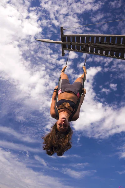 Aerial yoga beach workout - young attractive and healthy woman practicing aero-yoga training balance body and mind control hanging from ropes above the sea — Stock Photo, Image