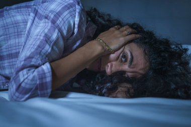 Genç üzgün ve depresif İspanyol kadının dramatik gece hayatı portresi. Yatakta uykusuz, uykusuz ve düşünceli depresyon acısı çeken endişeli bir kadın.