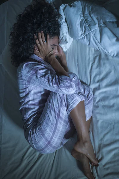 Drammatico stile di vita notturno ritratto di giovane donna ispanica triste e depressa con i capelli ricci insonni a letto sveglio e pensieroso sentimento preoccupato sofferenza depressione — Foto Stock