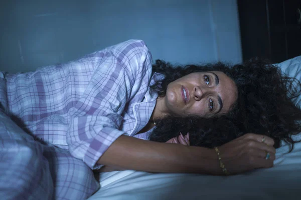 Драматический ночной образ жизни портрет молодой грустной и депрессивной латинской женщины с кудрявыми волосами, бессонными в постели, бодрствующей и вдумчивой, переживающей депрессию — стоковое фото