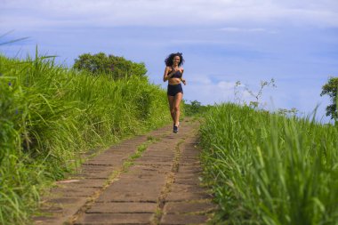 Kırsal yolda koşan mutlu bayan koşucu eğitimi - genç çekici ve formda koşan kadın dışarıda koşuyor sağlıklı yaşam tarzı ve spor açısından güzel bir pistte.