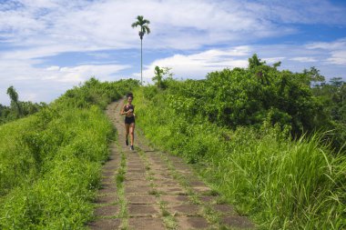 Kırsal yolda koşan mutlu bayan koşucu eğitimi - genç çekici ve formda koşan kadın dışarıda koşuyor sağlıklı yaşam tarzı ve spor açısından güzel bir pistte.