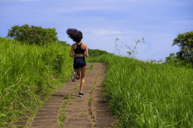 Kırsal yolda bayan koşucu eğitimi - genç çekici ve formda koşucu kadın dışarıda koşuyor sağlıklı yaşam tarzında güzel bir pistte.