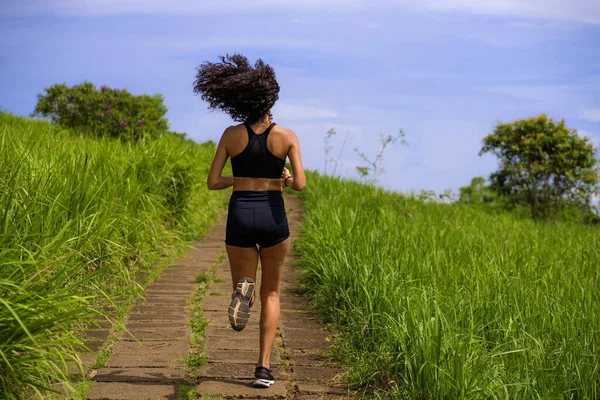 Bakifrån kvinnlig löpare utbildning på landsbygden väg - ung attraktiv och passform jogger kvinna gör löpning träning utomhus på vackra spår i hälsosam livsstil — Stockfoto
