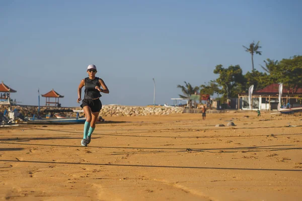 All'aperto fitness lifestyle ritratto di giovane donna attraente e atletica in compressione calze da corsa jogging sulla spiaggia facendo intervalli di allenamento nel concetto di allenamento atletico — Foto Stock