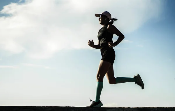 Dynamic silhouette of young attractive and athletic woman in compression running socks jogging happy on city park doing intervals workout in athlete training concept — Stockfoto