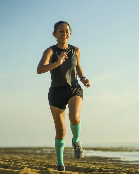 Al aire libre retrato de fitness de la joven atractiva y feliz mujer indonesia asiática en calcetines de compresión corriendo alegre en la playa haciendo ejercicio — Foto de Stock