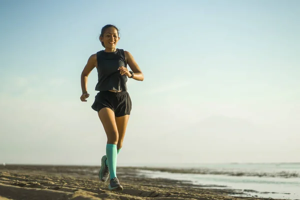 Al aire libre retrato de fitness de la joven atractiva y feliz mujer indonesia asiática en calcetines de compresión corriendo alegre en la playa haciendo ejercicio — Foto de Stock