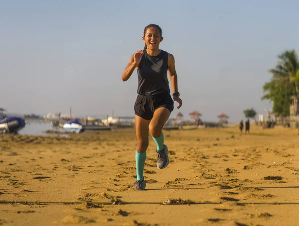 Potret kebugaran luar ruangan wanita muda Indonesia muda yang menarik dan bahagia dalam kaus kaki kompresi joging di pantai melakukan latihan — Stok Foto