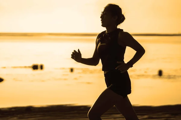 Çekici ve atletik Asyalı kadının silüeti sahilde koşuyor profesyonel atlet eğitimi ve sağlıklı yaşam tarzıyla sabah koşusu yapıyor. — Stok fotoğraf