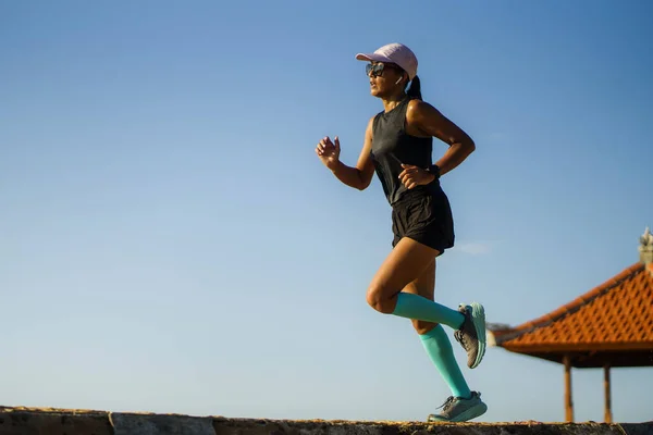 Retrato de fitness de la joven atractiva y atlética mujer asiática corriendo feliz en el parque haciendo ejercicios de intervalos al aire libre corriendo concentrado y centrado aislado en el cielo azul — Foto de Stock