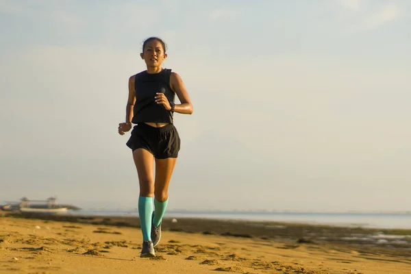 Al aire libre retrato de fitness de la joven atractiva y atlética mujer indonesia asiática en calcetines de compresión corriendo en la playa haciendo ejercicio de entrenamiento duro — Foto de Stock