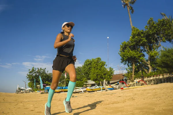 Outdoors fitness portrait of young attractive and athletic Asian Indonesian woman in compression socks jogging on the beach doing running workout training hard — Stok fotoğraf