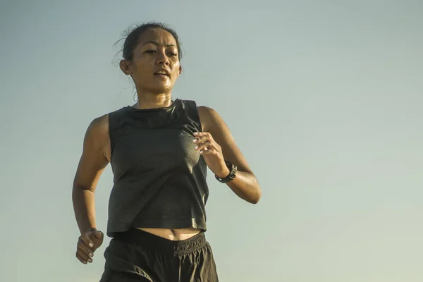Портрет молодої привабливої і атлетичної індонезійської жінки, якій за 40, що біжить на синьому тлі неба, з інтервалом тренувався в спортивній підготовці. — стокове фото