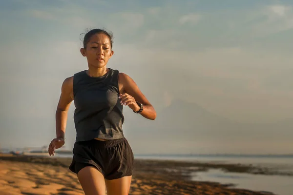 Outdoor-Fitness-Porträt der jungen attraktiven und athletischen asiatischen Indonesierin in ihren Vierzigern am Strand beim Intervalltraining im Athletentrainingskonzept — Stockfoto