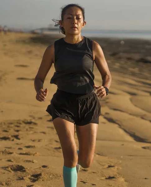 Портрет молодої привабливої та атлетичної індонезійської жінки, якій за 40, біжить на пляжі з інтервалом у спортивному тренуванні. — стокове фото