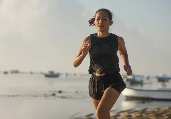 Szabadban fitness portré fiatal vonzó és sportos ázsiai indonéz nő a 40-es éveiben fut a strandon csinál időközönként edzés sportoló edzés koncepció — Stock Fotó