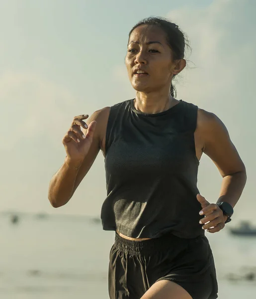 40 'larında Endonezyalı genç ve çekici bir Endonezyalı kadının açık hava fitness portresi. Sahilde koşuyor. Atletizm konseptinde antrenman yapıyor. — Stok fotoğraf
