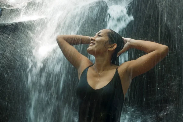 Молодая привлекательная и счастливая азиатская индонезийская женщина, пораженная красотой природного водопада в тропических джунглях, наслаждаясь удивительным и экзотическим местом для путешествий — стоковое фото