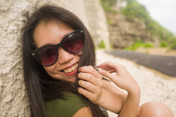 close up face portrait outdoors of young beautiful and happy Asian Chinese woman smiling cheerful looking playful and relaxed wearing chic sunglasses looking at the camera having fun