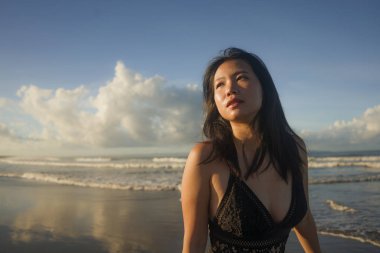 Güzel plaj cennetinde yürüyen, çekici ve havalı Asyalı bir kadın. Egzotik seyahat noktasında tatilin tadını çıkarıyor.