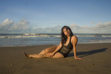 Çekici ve mutlu Asyalı Japon kadının doğal hayat tarzı portresi. Güzel kumsal cennetinde mayo giymiş, kumsalda oynaşıyor. Rahatlıyor ve keyifli tatillerin tadını çıkarıyor. 