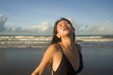 Çekici ve mutlu Asyalı bir kadının doğal yaşam tarzı portresi. Mayo giymiş güzel bir plaj cennetinde yürüyor. Rahatlamış ve keyifli tatillerin tadını çıkarıyor. 