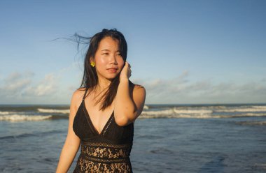 Güzel bir plaj cennetinde mayo giymiş genç ve mutlu Asyalı bir kadının doğal yaşam tarzı portresi. Rahatlamış ve keyifli tatiller geçiriyor. 