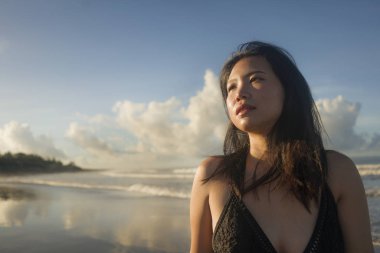 Güzel sahil cennetinde yürüyen mayo giymiş çekici ve havalı Asyalı bir kadın. Egzotik seyahat noktasında tatilin tadını çıkarıyor.