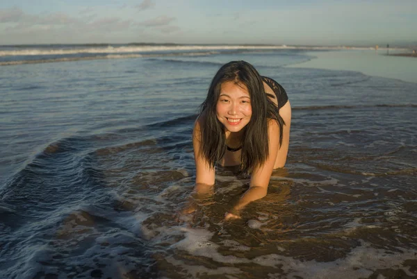 身穿泳衣的年轻迷人而快乐的亚裔中国女人跪在沙滩上 享受着美丽的海滨天堂般的放松与欢乐 享受着无忧无虑的假期 — 图库照片