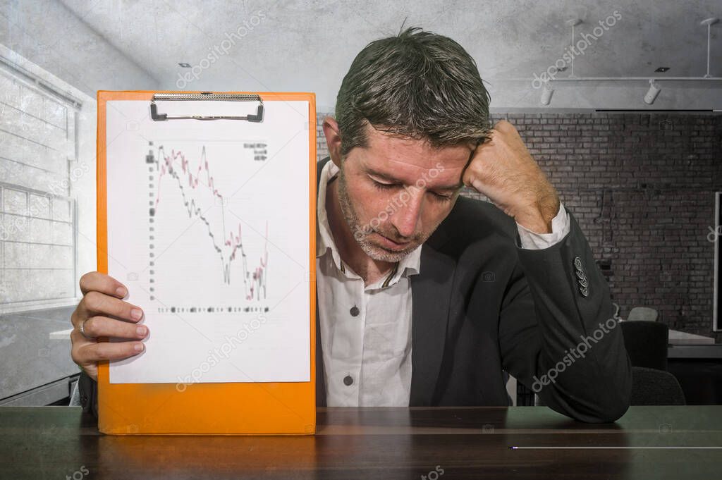 depressed and worried businessman holding clipboard showing graph reporting company financial crisis and problems feeling concerned and frustrated in corporate work difficulties concept