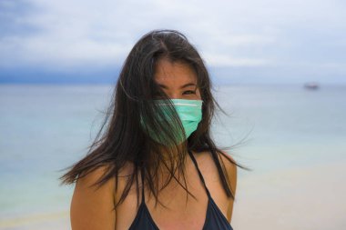 Halka açık yerlerde tıbbi maske kullanmak. Genç Asyalı çekici bir kadın. Plaj tatillerinde bikini giyiyor ve virüs enfeksiyonunu önlemek için koruyucu maske takıyor. 