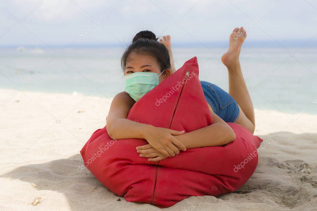 use of medical face mask in public places- young attractive Asian Korean woman enjoying beach holidays wearing bikini and protective facial mask in prevention vs virus infection 