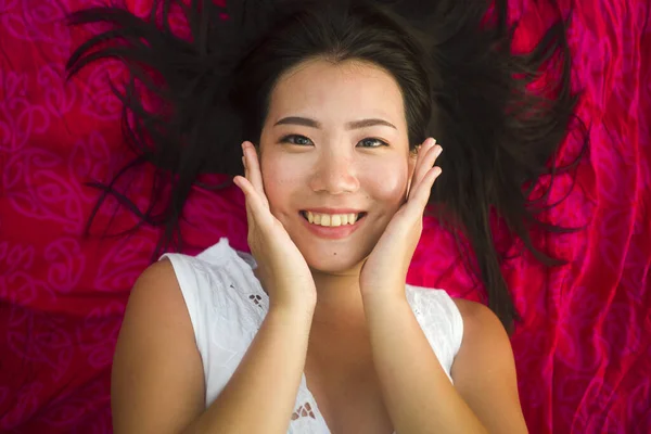 outdoors fresh and natural portrait of young beautiful and happy Asian Cchinese woman lying flat on sarong on beach sand smiling cheerful and relaxed in beauty and fashion concept