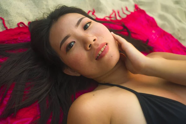 身穿比基尼的年轻 快乐的亚裔韩国女人平躺在沙滩上的沙隆上 笑容满面 洋洋洒洒地笑着 洋溢着美感和时尚气息 — 图库照片