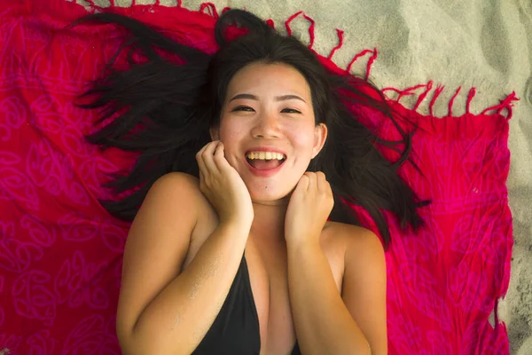 身穿比基尼的年轻 快乐的亚裔韩国女人平躺在沙滩上的沙隆上 笑容满面 洋洋洒洒地笑着 洋溢着美感和时尚气息 — 图库照片
