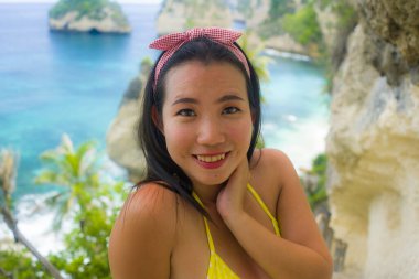 Bikinili güzel ve mutlu Asyalı Japon kadının yaz tatili portresi elmas şekilli kayalık uçurumlu tropik cennet sahnesine baktığında inanılmaz deniz manzarası seyrediyor.