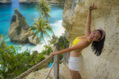 Güzel ve mutlu Asyalı bikinili bir kadının yaz tatili portresi. Muhteşem deniz manzarasının tadını çıkarıyor. Tropik cennet sahili, elmas şekilli kaya uçurumu manzaralı.