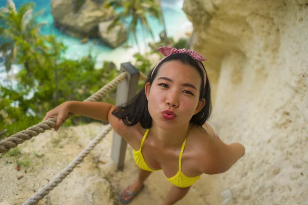 ビキニの若い美しく幸せなアジア系中国人女性の夏休みの肖像は ダイヤモンドの形の岩の崖と熱帯の楽園ビーチの観点から素晴らしい海のシーンを楽しんで — ストック写真