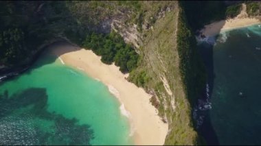 Nusa Penida 'nın Kelingking sahilinde Asya' da egzotik tatil seyahatleri ve tropikal hedef kavramında harika bir deniz uçurumunun üzerinde uçan güzel bir insansız hava aracı görüntüsü.